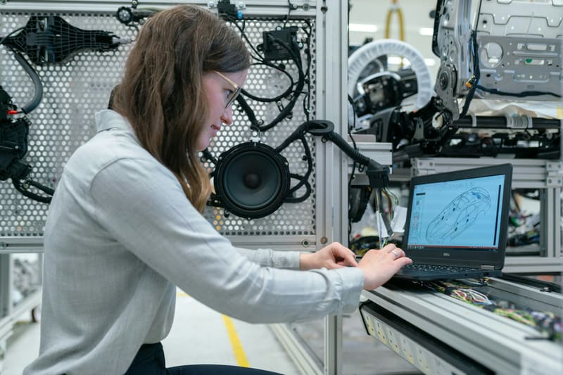 A woman reviewing a 3D vehicle model on a laptop — licensed illustration, not a person in the BLS count. Oklahoma.