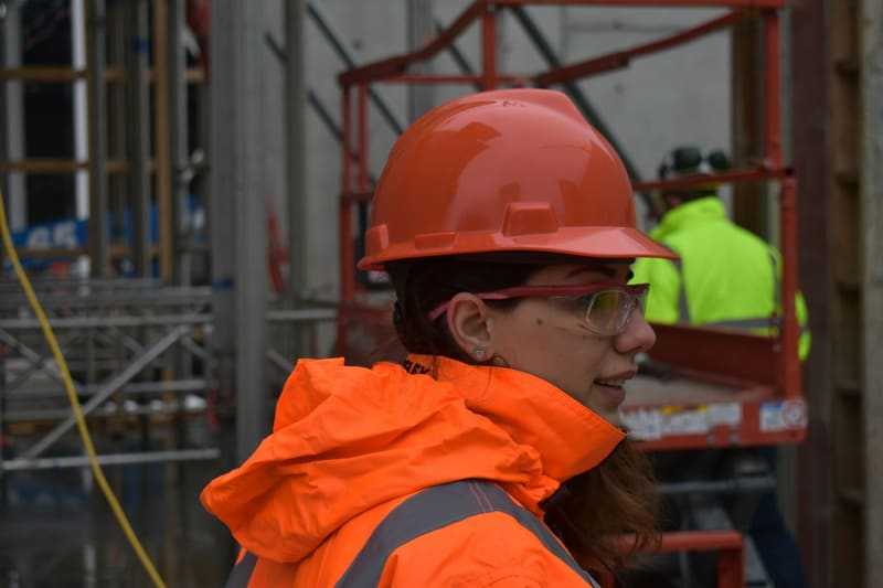 A woman working on a construction site in a hard hat — licensed illustration, not a person in the BLS count. Campaign hub portrait grid.